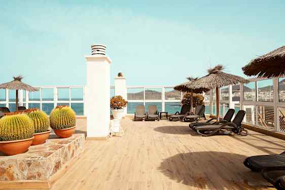 Terrass med solstolar, parasoller och utsikt över havet. (AI-genererad text)