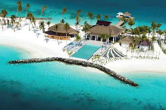 Flygbild över en tropisk resort vid havet med en pool, vita stränder och palmer. (AI-genererad text)