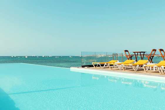 Pool med utsikt över havet och solstolar vid sidan. (AI-genererad text)