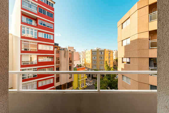 Vy från en balkong med flera byggnader och en blå himmel i bakgrunden. (AI-genererad text)