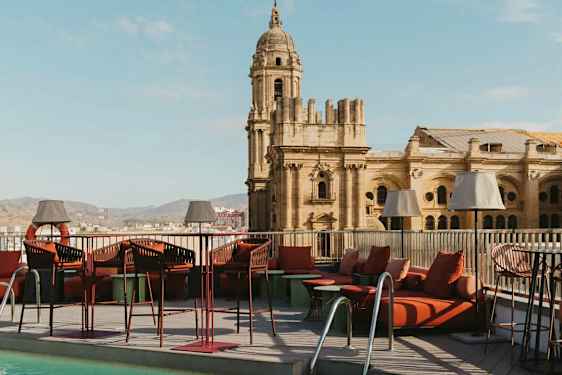 En takterrass med pool och loungemöbler, med en historisk byggnad i bakgrunden. (AI-genererad text)