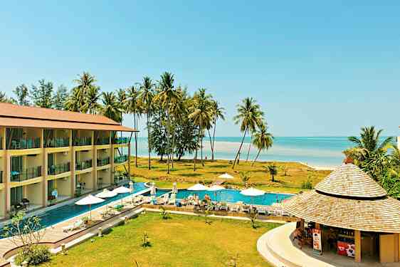 En resort med en pool, solstolar och parasoller, nära stranden med palmer. (AI-genererad text)