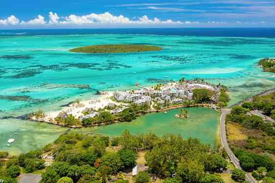 Flygbild över en strandresort omgiven av turkost vatten och grönska. (AI-genererad text)