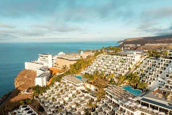 Hotellkomplex på en klippa med pooler och havsutsikt. (AI-genererad text)