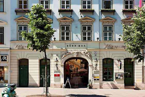 Ett stråhatt klädd byggnad med valv och fönster, blommor dekorerar fönsterkarmarna. (AI-genererad text)