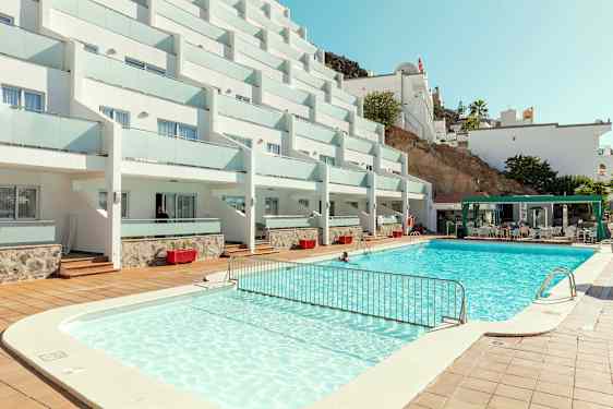 Bild på hotellkomplex med pool och sittområde. (AI-genererad text)