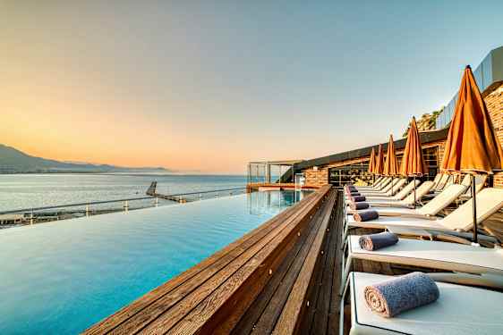 Strandnära poolområde med solstolar och orange parasoller. (AI-genererad text)