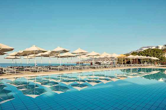 Solstolar och parasoll vid en pool med utsikt över havet. (AI-genererad text)