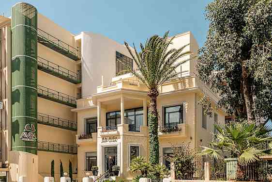 Bild på en hotellbyggnad omgiven av palmer. (AI-genererad text)