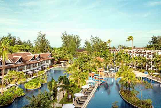 Hotellområde med en stor pool omgiven av palmer och byggnader. (AI-genererad text)