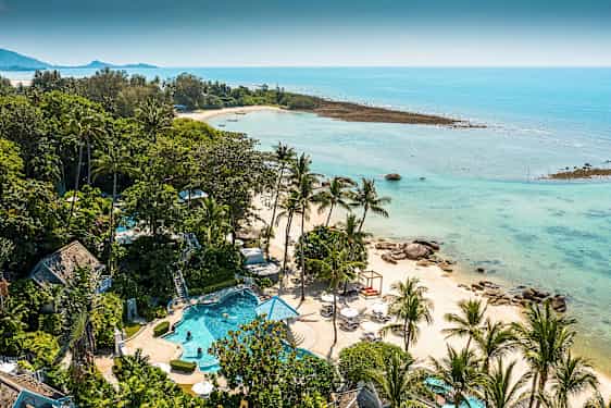 Ett tropiskt landskap med en strand som kantas av palmträd och klarblått vatten. Det finns en pool och gröna områden i förgrunden. (AI-genererad text)