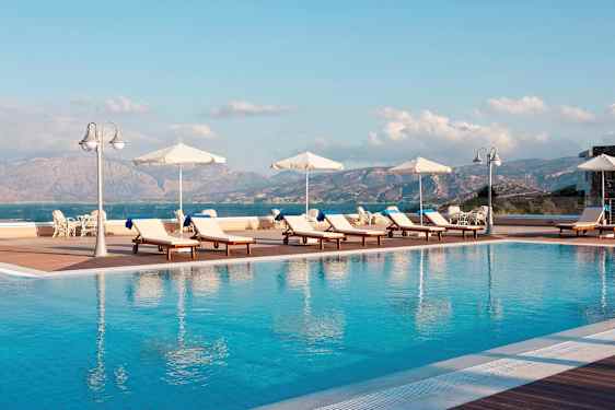 Solstolar och parasoller vid en utomhuspool med utsikt över berg och hav. (AI-genererad text)