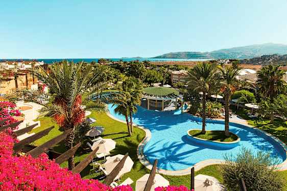 Bild på hotellområde med en stor pool och palmer, samt utsikt mot havet. (AI-genererad text)