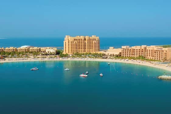 Hotellkomplex vid en sandstrand och havsvik. (AI-genererad text)