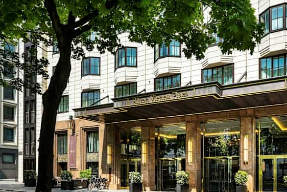 En hotellbyggnad med en elegant entré, omgiven av träd. (AI-genererad text)