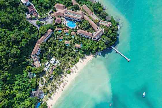 Flygbild av en resort vid en sandstrand och turkost vatten. (AI-genererad text)