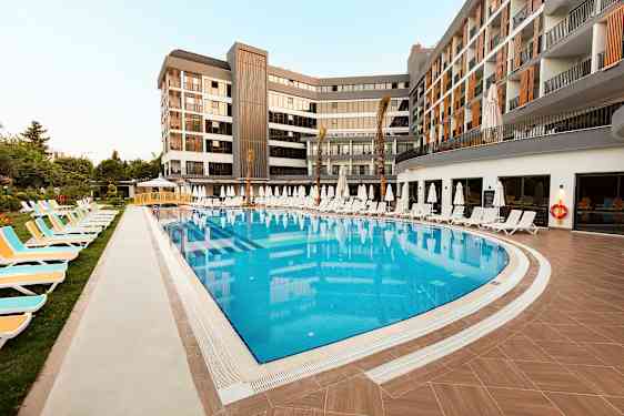 Utomhuspool omgiven av solstolar och parasoller vid ett modernt hotell. (AI-genererad text)