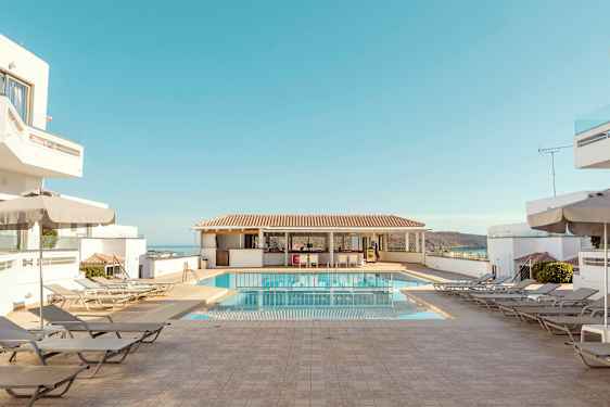 Hotellpoolområde med solstolar, parasoller och blå himmel. (AI-genererad text)