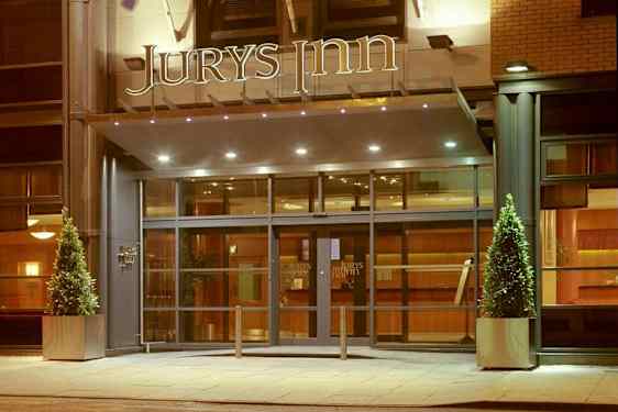 Hotellentré med glasdörrar och skylten 'Jurys Inn' ovanför. (AI-genererad text)