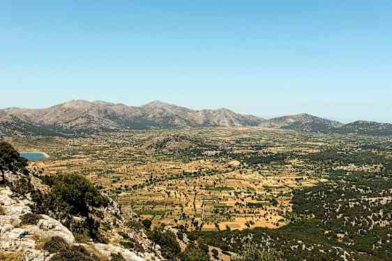 En vidsträckt dal omgiven av berg med betesmarker och odlingsfält. (AI-genererad text)