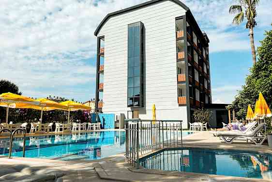 En byggnad vid en pool med solstolar och parasoller på terrassen. (AI-genererad text)