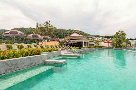 Poolområde med solstolar och parasoller och en liten bar i bakgrunden. (AI-genererad text)