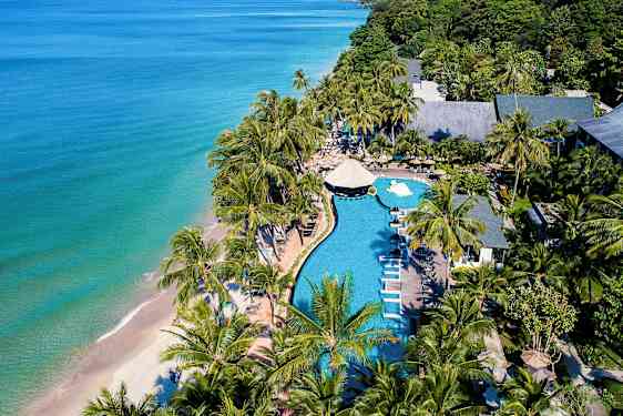 Flygbild över en strandresort med pool, solstolar och palmer nära havet. (AI-genererad text)