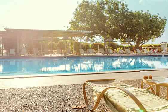 En solstol och ett bord vid kanten av en pool. (AI-genererad text)