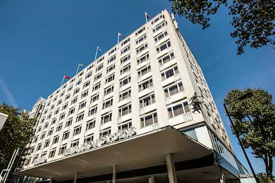 Flerbostadshus med synliga fönster och flaggor på taket. (AI-genererad text)