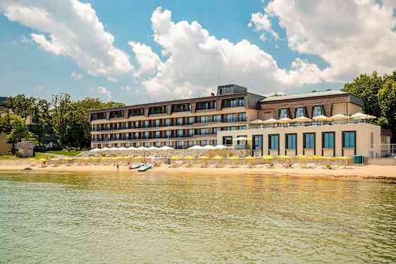 Flerfaldigt våningshotell vid stranden med gula parasoller och klarblå himmel. (AI-genererad text)