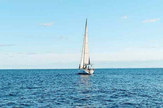 En segelbåt seglar på ett öppet hav under en klar himmel. (AI-genererad text)