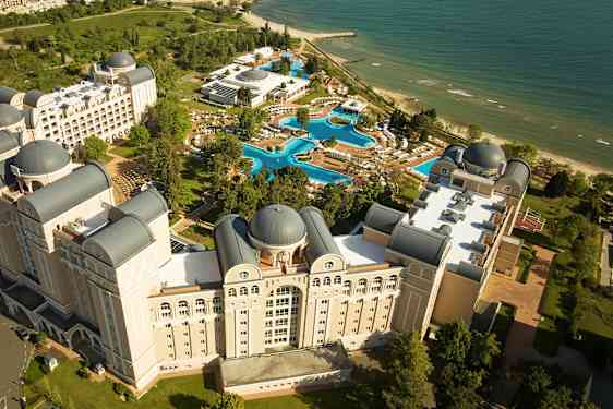 Vy från ovan av ett hotellkomplex med pooler och strand. (AI-genererad text)