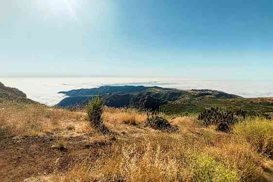 Solig bergsutsikt med molnigt panorama och torr vegetation. (AI-genererad text)