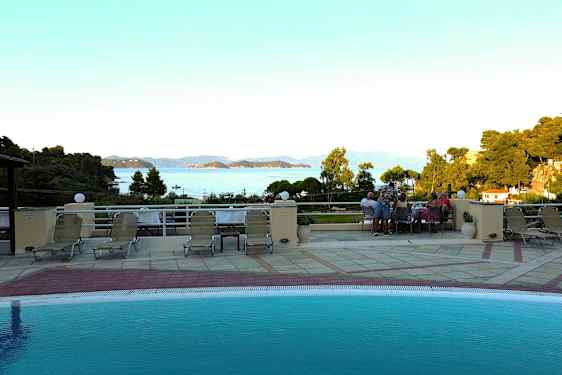 Utsikt från en poolterrass med solstolar, med hav och öar i bakgrunden. (AI-genererad text)