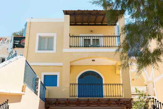 Gult hus med blå dörrar och balkonger. (AI-genererad text)