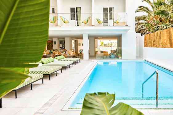 Utomhuspool vid hotell med solstolar och grönskande omgivning. (AI-genererad text)