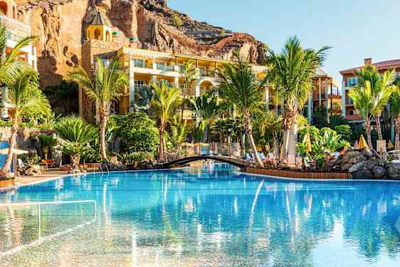 En pool omgiven av palmer och semesterbostäder. (AI-genererad text)