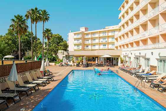 En hotellbyggnad syns bredvid en utomhuspool med solstolar och parasoller runt omkring. (AI-genererad text)