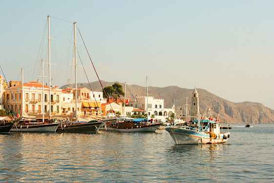 En hamn med båtar och byggnader, berg syns i bakgrunden. (AI-genererad text)