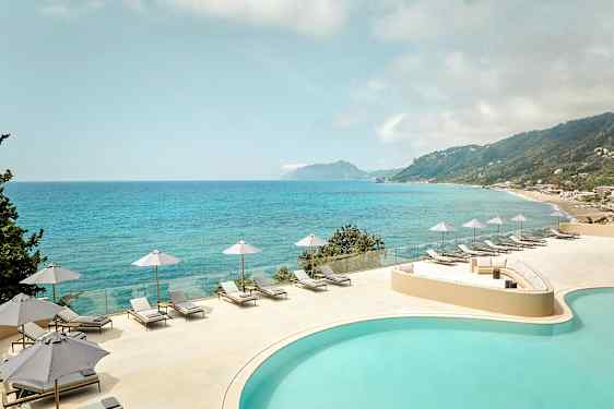 Utsikt över en pool och hav med solstolar och parasoller på en terrass. (AI-genererad text)