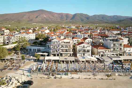 Vy över en stad med flera vitmålade byggnader och röda tak, framför berg i bakgrunden. (AI-genererad text)