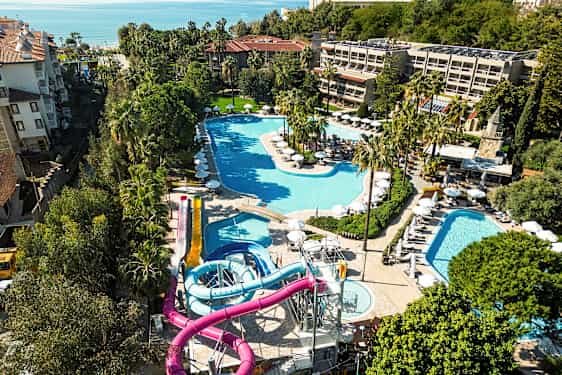 Vy över en resort med flera pooler och vattenrutschbanor, omgiven av grönska. (AI-genererad text)