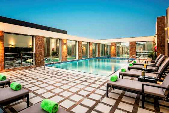 Utomhuspool omgiven av solstolar och byggnader. (AI-genererad text)