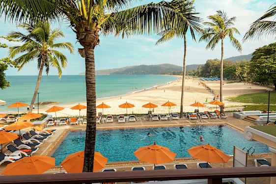 En strand med en pool i förgrunden, omgiven av solstolar och parasoller. (AI-genererad text)