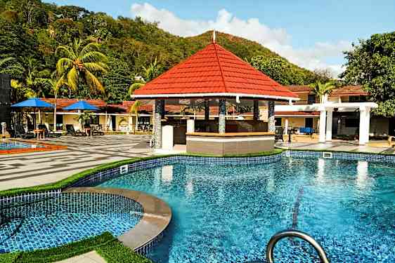 Swimmingpool med ett poolbarområde och omgivande tropiska träd. (AI-genererad text)