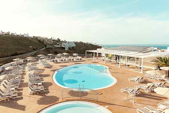 Poolområde med solstolar och parasoller på terrass med havsutsikt. (AI-genererad text)