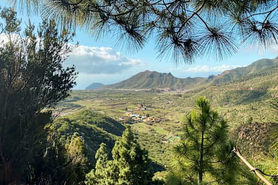 Vy över ett grönt dalområde med byar och berg i bakgrunden. (AI-genererad text)