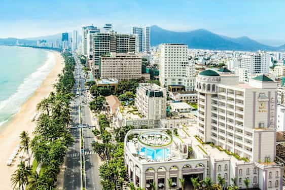 Bild av en stad vid havet med moderna byggnader och en strand med parasoller. (AI-genererad text)