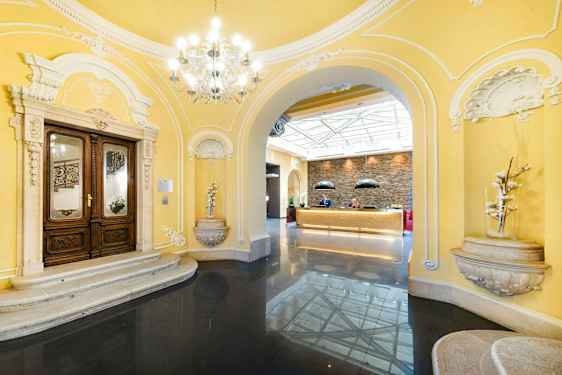 Entréområde med klassiska arkitektoniska detaljer och reception i en ljus miljö. (AI-genererad text)