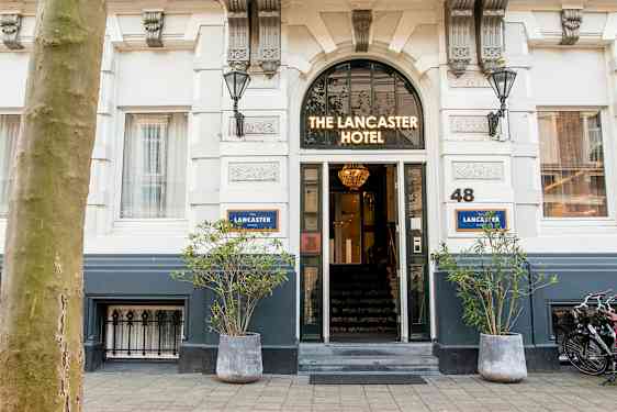 Entré till ett hotell med skylten 'The Lancaster Hotel' ovanför dörren. (AI-genererad text)